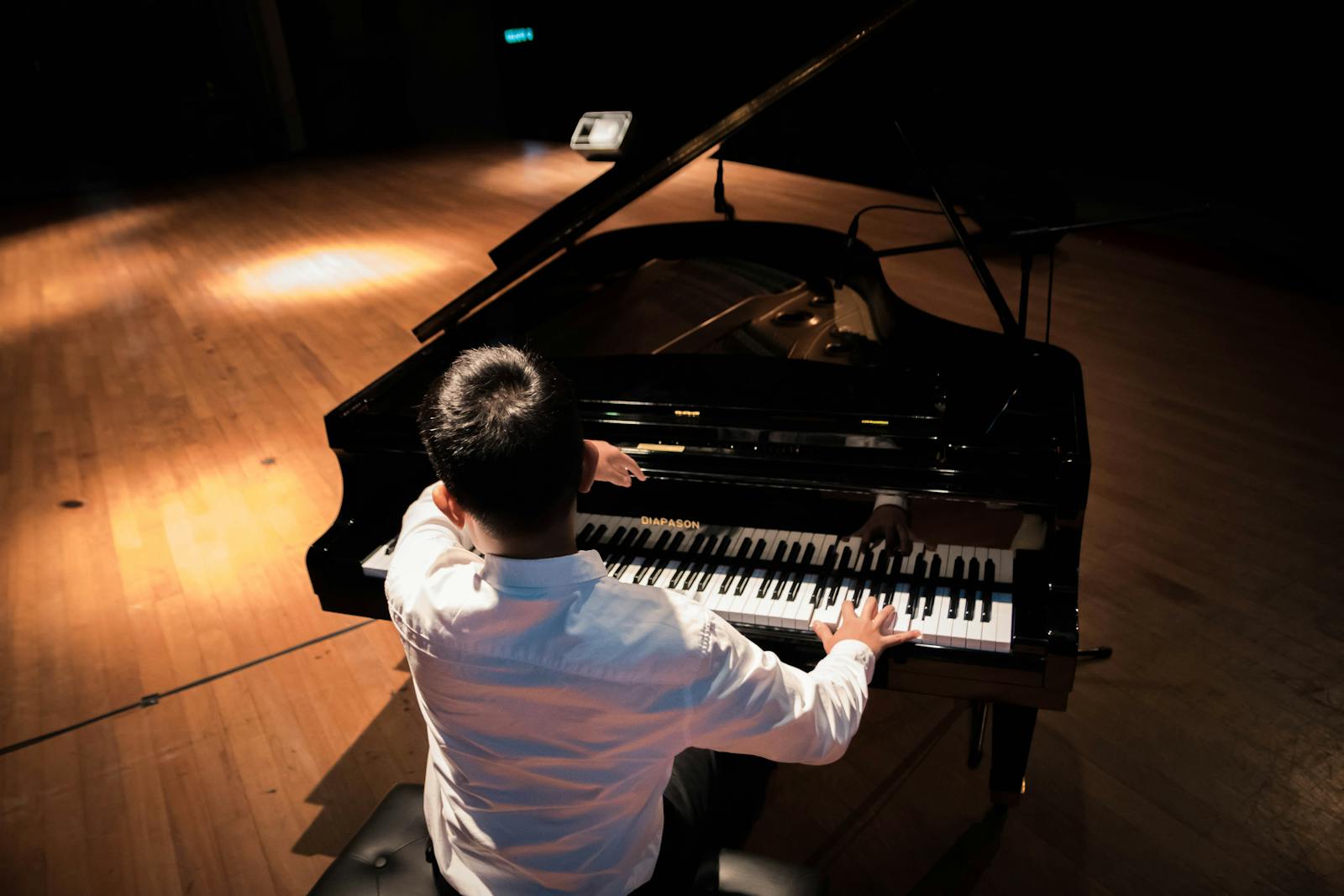 Pianist performing on a grand piano under warm stage lighting