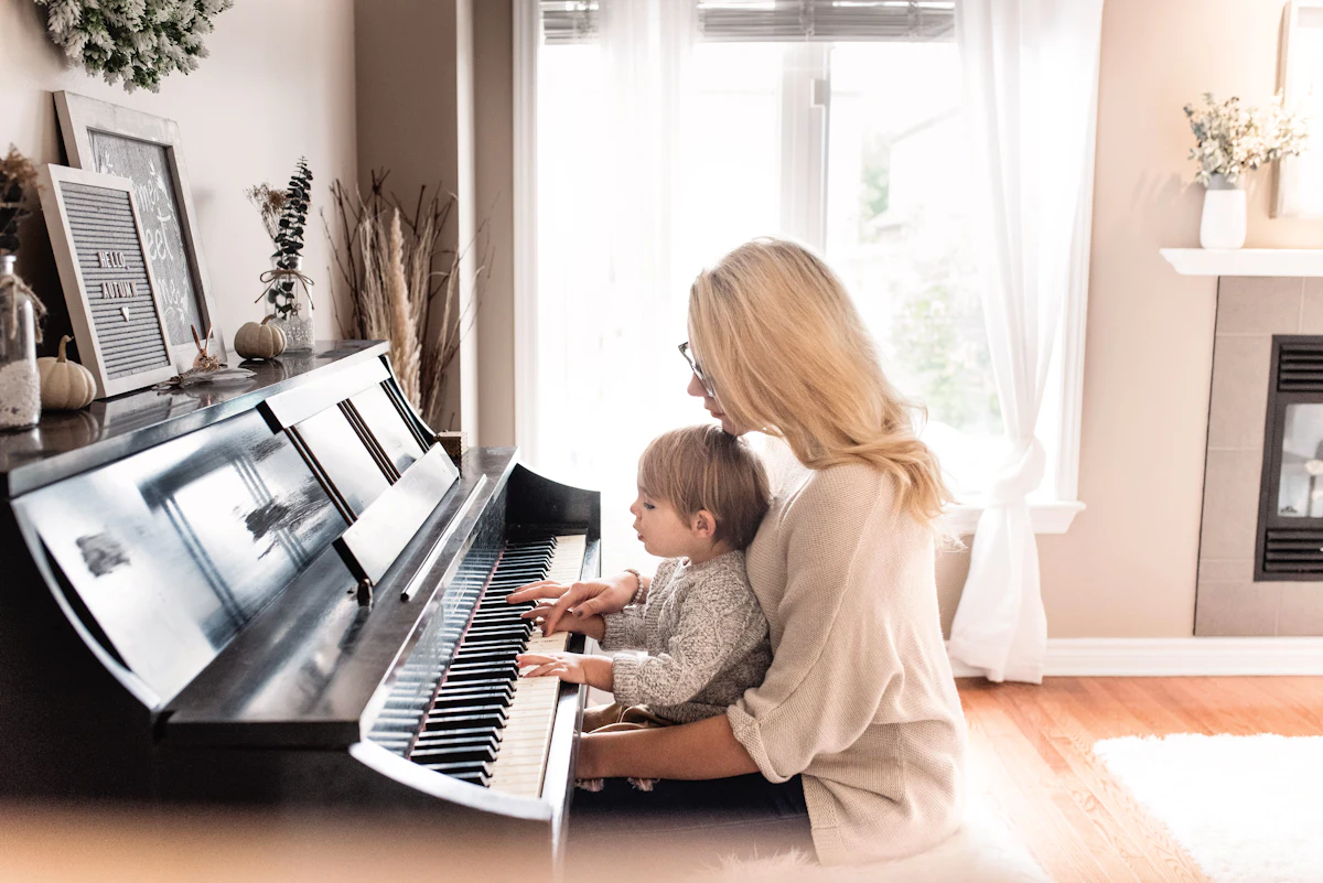 A child practicing piano at home with a teacher